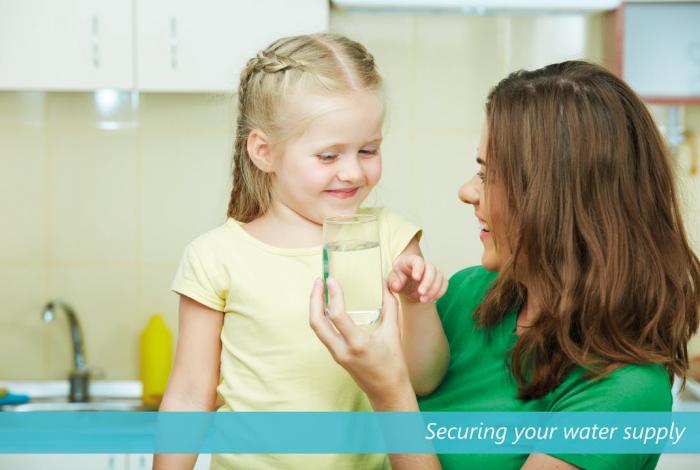 Young girl and mother holding glass of water