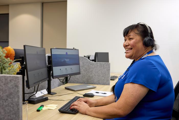 woman sitting at computer with headset on smiling